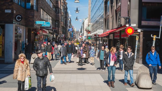 Shoppers and tourists strolling through the spring sunshine on the pedestrianised shopping street of Drottninggaten in the heart of Stockholm.