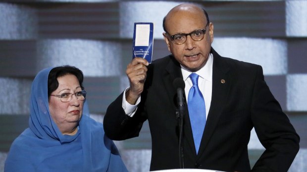 Khizr Khan, father of fallen US Army Captain Humayun S. M. Khan holds up a copy of the Constitution of the United States as his wife listens during the Democratic National Convention. 