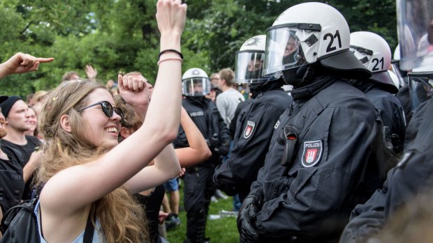 A girl dances to techno music in front of the police.