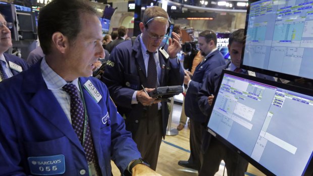 Specialist Glenn Carell, foreground, works with traders at his post that handles Twitter, on the floor of the New York Stock Exchange.