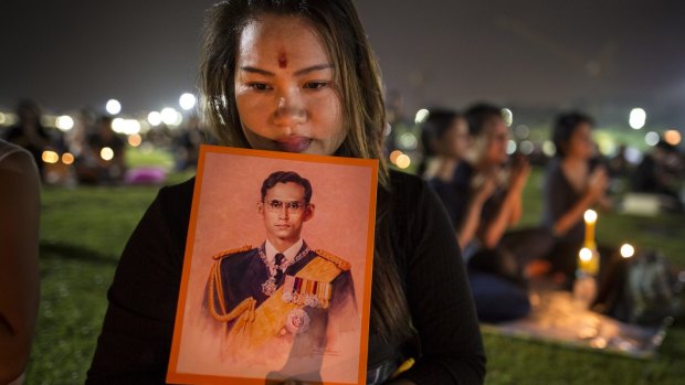 Nation in mourning: A Thai woman holds up a picture of the late king in Bangkok.