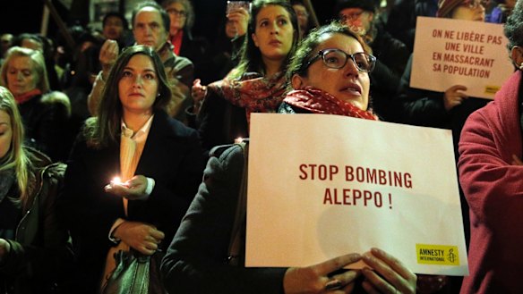 People hold poster and candles during a gathering in Paris in December.