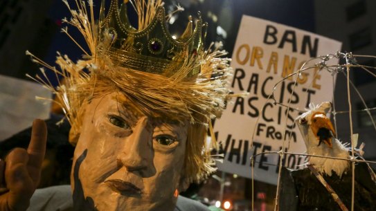 A demonstrator wearing a mask in the likeness of US President Donald Trump protests against his executive order in Los Angeles.