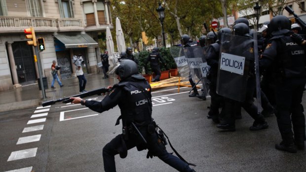 A Spanish riot police officer shoots rubber bullet at people trying to reach a voting site at a school assigned to be a polling station by the Catalan government in Barcelona.