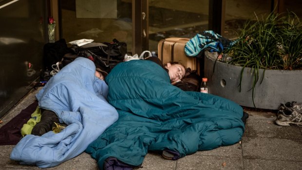 A couple sleep through the mid-morning on the corner of Collins and King Streets.
