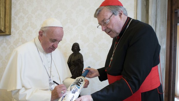 Perhaps it should have been a broom. Pope Francis signs a cricket bat he received from Cardinal George Pell at the Vatican.