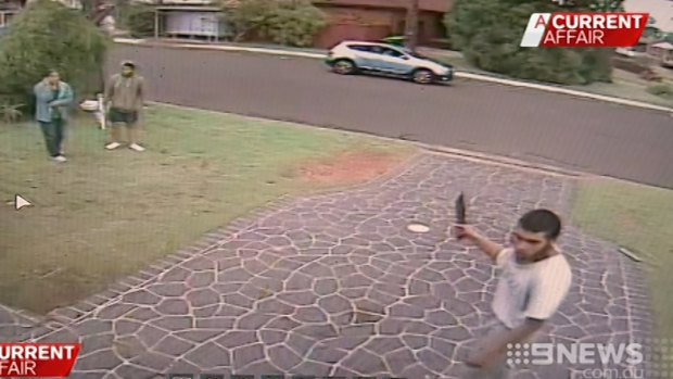 Neighbours watch as Ihsas Khan stands outside the hair salon.