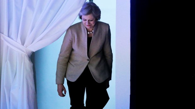 Theresa May enters the room through a curtain to deliver her speech.