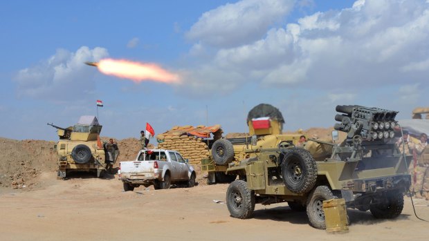 Iraqi government forces and allied militias fire against IS militants.