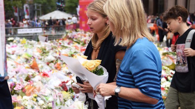 Madeleine Pulver, victim of the collar bomb incident, fights back tears before placing flowers near the scene of the Martin Place siege with her mother on Thursday.