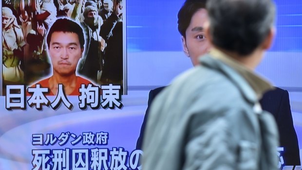 A pedestrian looks at a TV screen in Tokyo showing an image of Japanese journalist Kenji Goto, who is being held by Islamic State militants.