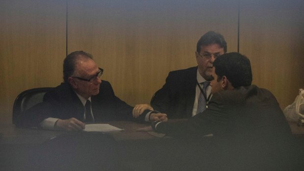 Carlos Nuzman, left, talks to his lawyers at Federal Police headquarters in Rio de Janeiro on Tuesday.