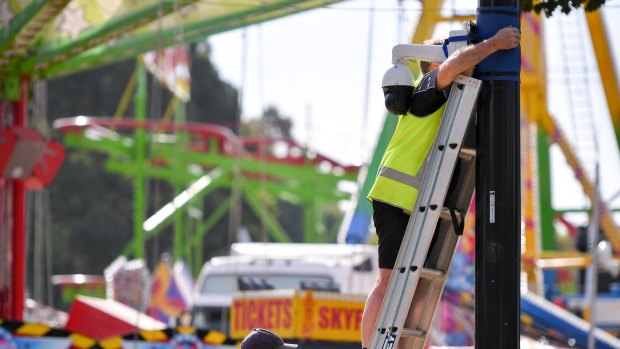 Workers install CCTV near the fun rides at the Moomba festival.