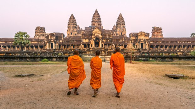 Three buddhist monks have Angkor Wat to themselves at sunrise.