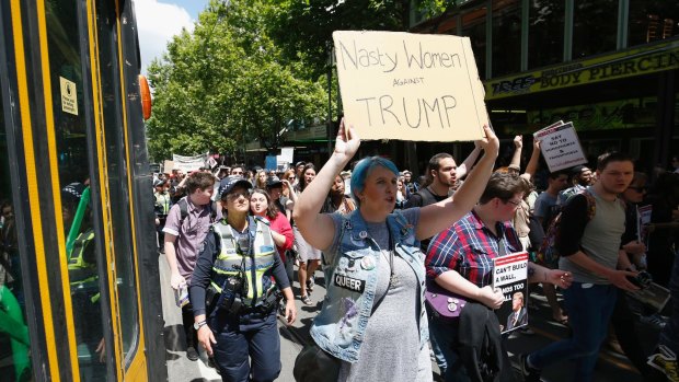 Protesters against Donald Trump walk along Swanston Street stopping trams. 