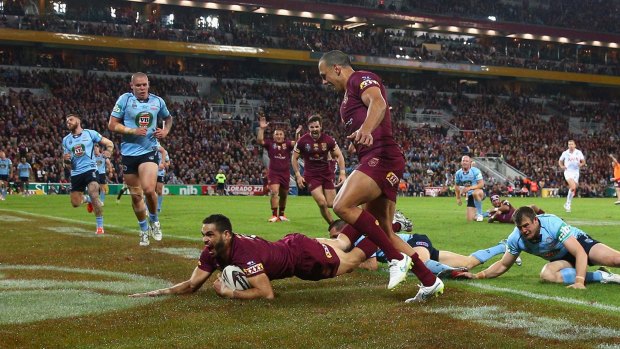 Unstoppable: Greg Inglis slides over for Queensland's third try.