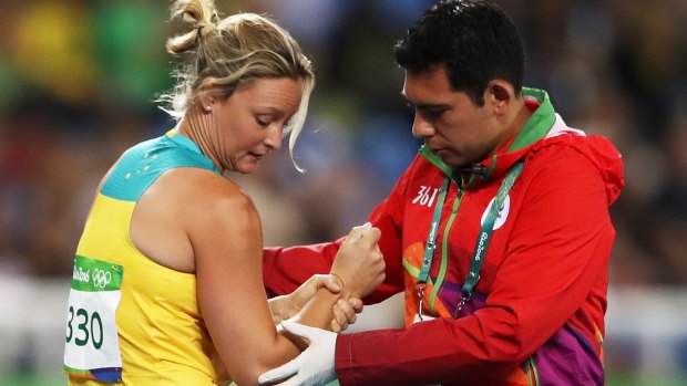 Kim Mickle of Australia is assisted by medical staff after popping her shoulder in the javelin. 