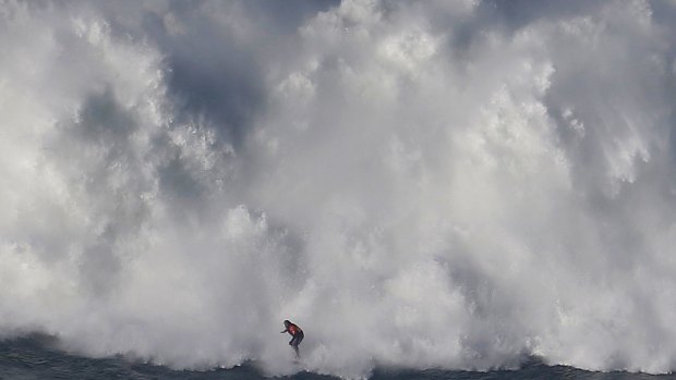  A surfer is dwarfed by a massive wave at Praia do Norte in Portugal.