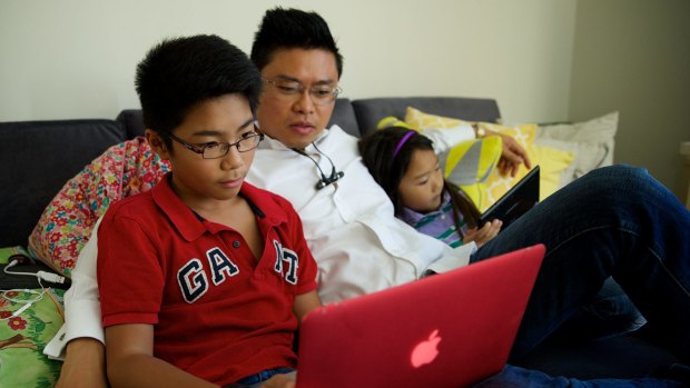 Joss,12, and Darcy Nguyen, 7, often do school research online with their father Tung Nguyen on their tablet or laptop using the NBN.