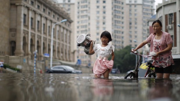A child carries kettles through a flooded street with a woman in Tianjin, China, in July. 