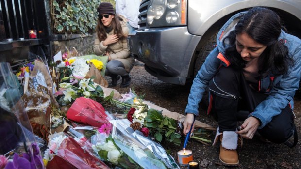 A woman lights a candle as tributes of flowers are left at the home of the pop music icon.