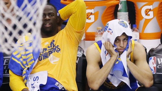 Golden State Warriors' Draymond Green, left, and Stephen Curry watch the action from the bench.