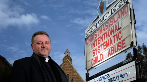 Gosford Anglican Church priest Rod Bower with an earlier billboard in 2014.