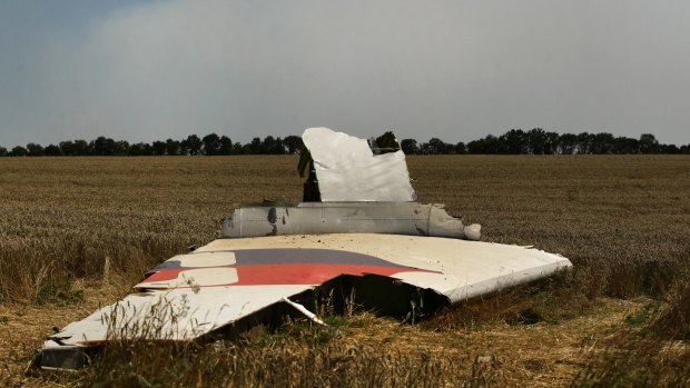 A portion of the MH17 wing lies in the field as smoke rises behind the tree-line. Russians no longer know what to think.