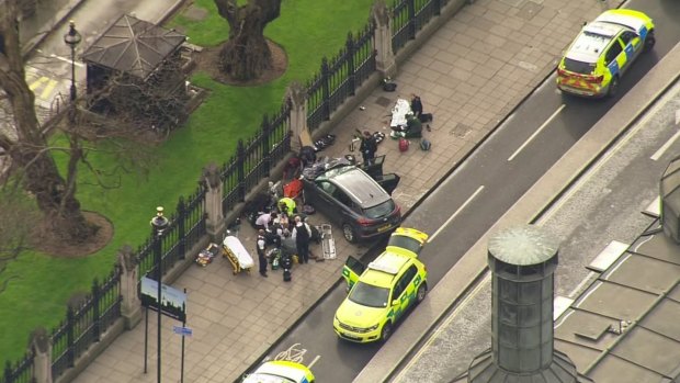 In this image taken from video, police officers gather around a car adjacent to Houses of Parliament in London.