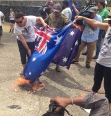 Protesters burn the Australian flag.