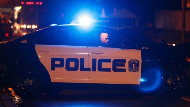 An officer sits in his car at the scene of one of the police shootings in Des Moines.