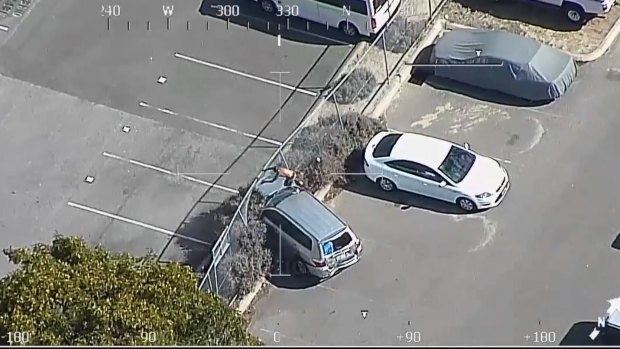 Police helicopter footage captures the man on top of a car about to jump a fence.