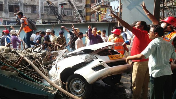 Locals and rescue workers clear the rubble of a partially collapsed overpass in Kolkata.