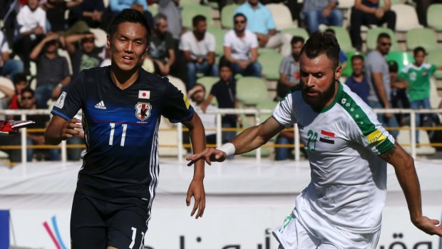 Japan's Yuya Kubo, left, and Iraq's Waleed Salim Al-Lami compete for the ball. 