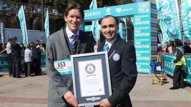 Matthew Whitaker with his Guinness World Record certificate after completing the Sydney Running Festival marathon wearing a suit.