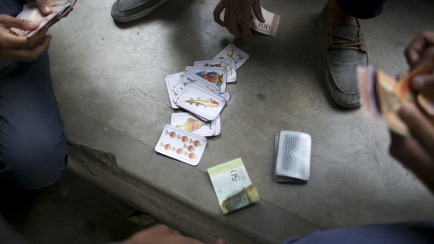Boys gamble on a card game in the patio of their public high school in Caracas, Venezuela. As many as 40 per cent of teachers skip class on any given day to wait in food lines.