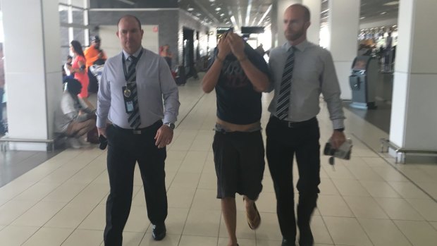 Murder accused Chris Lavery is escorted through Cairns Airport by Victoria Police homicide squad detectives