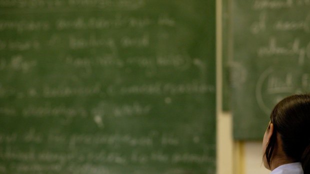 A student looks on at a blackboard in a class room.