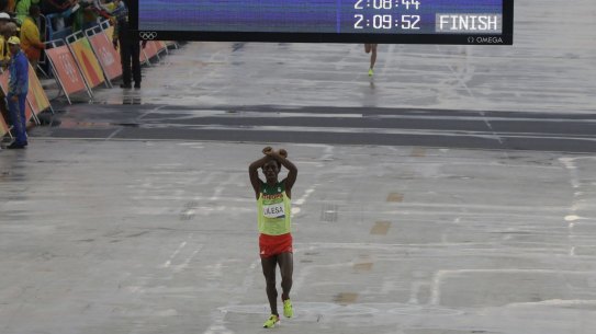 Moment of protest: Ethiopia's Feyisa Lilesa crosses his arms as he crosses the finish line.