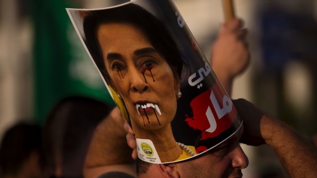 A member of the Islamic Movement in Israel holds a defaced poster of  Aung San Suu Kyi during a demonstration in Tel Aviv.