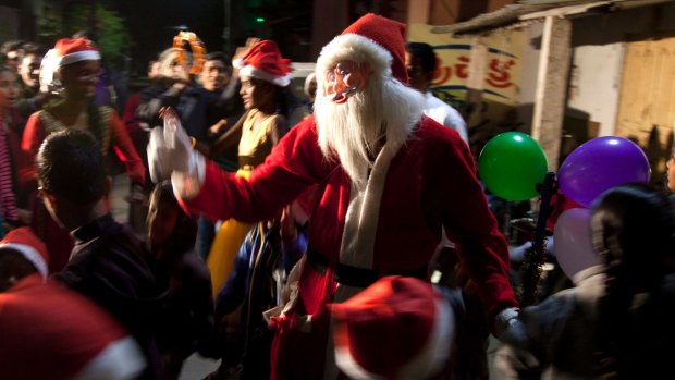An Indian man dressed as Santa sings Christmas carols with children during Christmas celebrations in Hyderabad, India. 