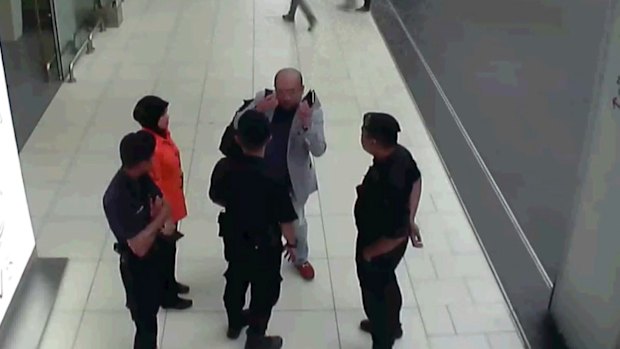 Kim Jong-nam, in grey, gestures towards his face while talking to airport security shortly before his death.