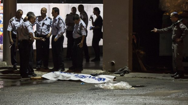Israeli police stand by the shrouded body of a Palestinian attacker in Beersheba, Israel.