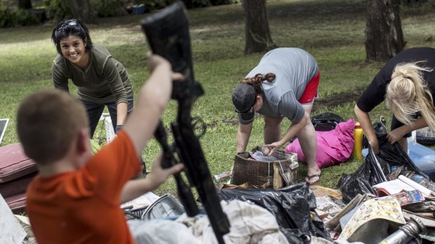 Sonia Porter (left) reacts to Devin Sadler, 9, picking up a waterlogged gun during clean-up efforts at John and Ruth Hansen's flood damaged home in San Marcos, Texas.