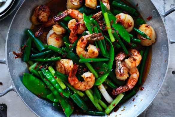 Neil Perry's spicy stir fried prawns and scallops with garlic stems, spring onions and snow peas.