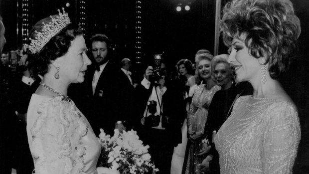 Joan Collins meets Queen Elizabeth II at London's Theatre Royal in 1985.