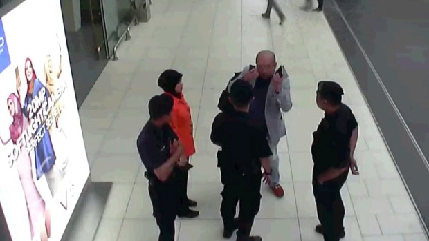 In this image made from security camera footage, Kim Jong-nam gestures towards his face while talking to airport security at Kuala Lumpur International Airport.