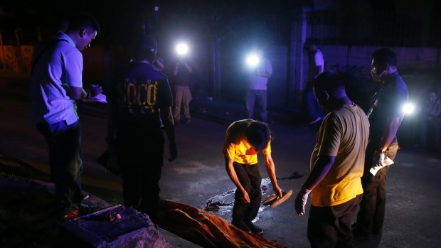 Funeral workers prepare to remove the body of a crime suspect after he was killed in gunbattles late in Manila, Philippines.