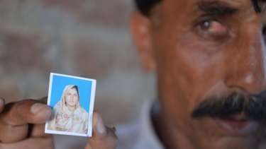 Twice widowed: Pakistani Mohammad Iqbal   holds up an image of his wife Farzana Parveen.