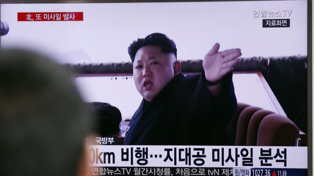 A man watches a TV news program showing file footage of North Korean leader Kim Jong-un. 
